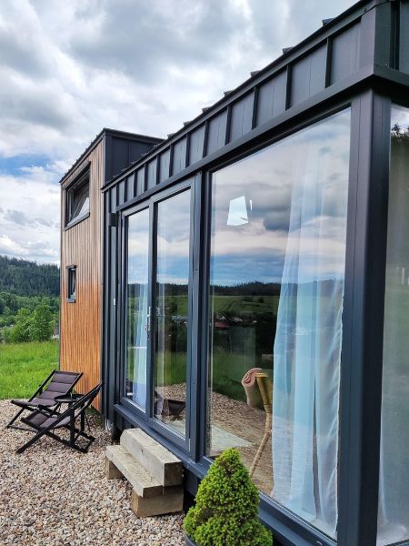 Tiny House mit Empore – Panorama-Fensterfront über volle Höhe – Zeitgenössischer Chalet-Stil